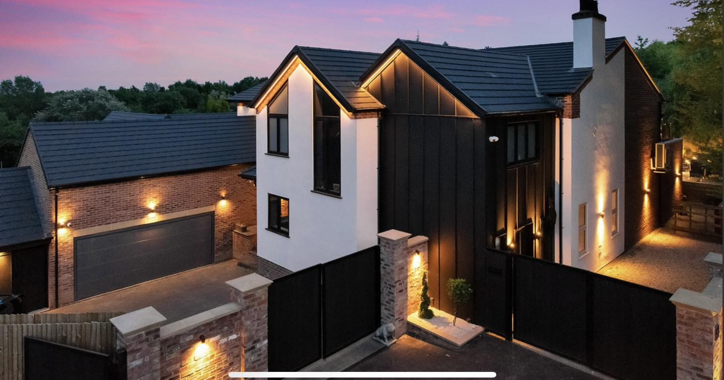 Contemporary UK home with warm lighting, timber cladding and a landscaped entrance