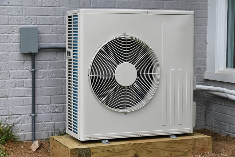Neatly installed air source heat pump beside a residential property